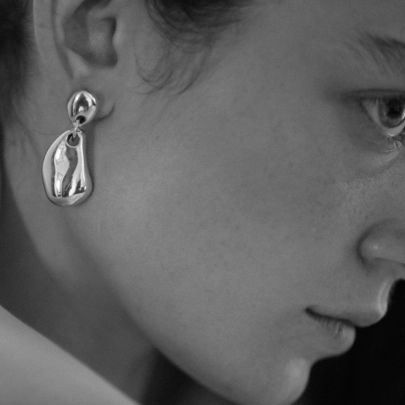 Woman wearing AGMES 0.925 sterling silver sculpted round drop earrings.