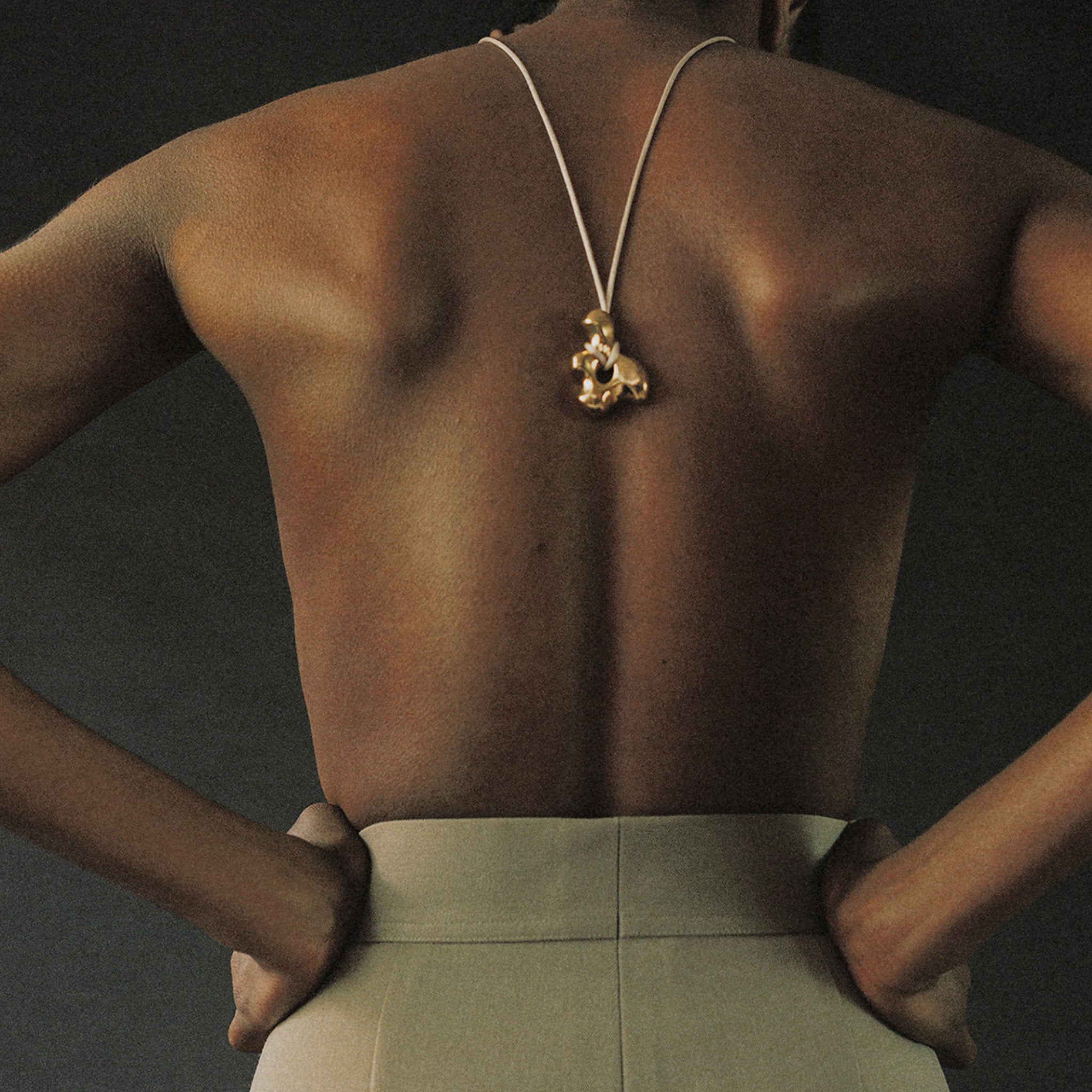Person wearing AGMES 18k Gold Vermeil sculpted pendant on Ivory satin cord. Simone Bodmer-Turner.