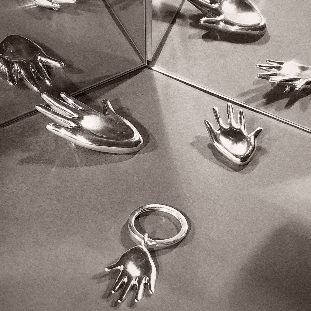 AGMES .925 sterling silver sculptural hand shaped Large Dali Brooch, Dali Brooch, and Dali Keychain on grey reflective background.