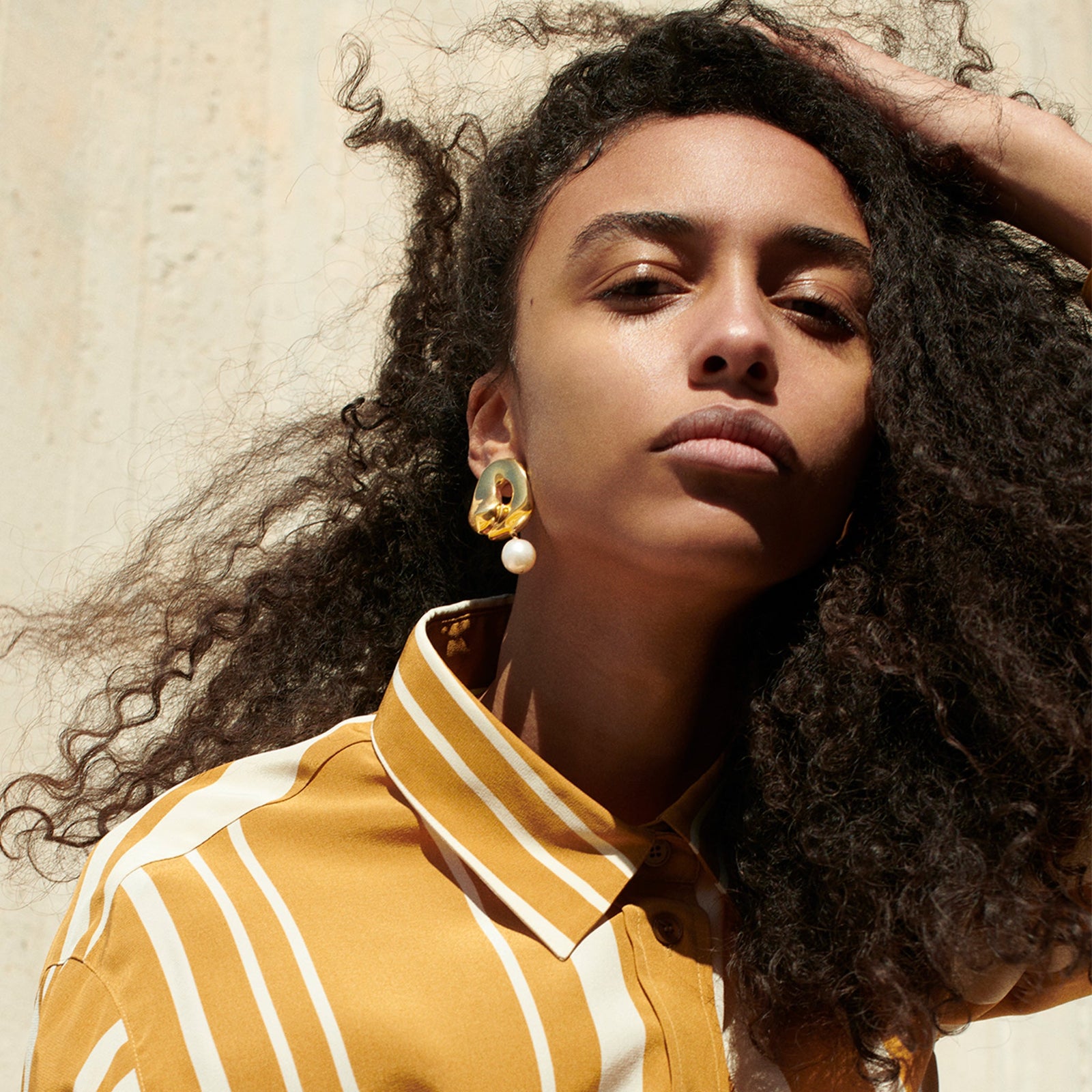 Woman wearing AGMES 18k gold vermeil sculpted Gertrude pearl drop earrings. Simone Bodmer-Turner.