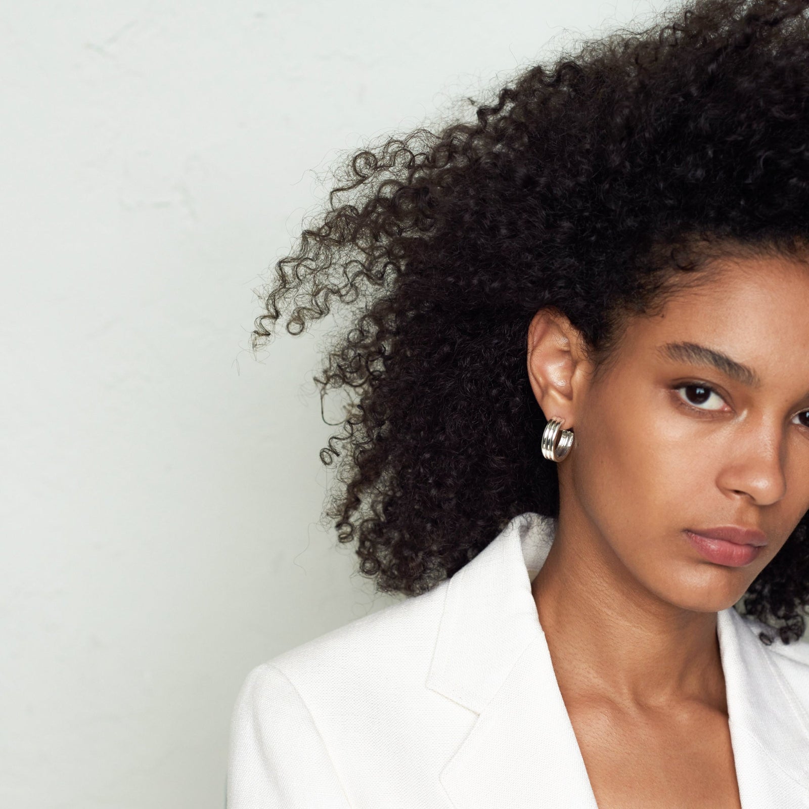 Woman wearing AGMES 0.925 sterling silver triple ridged medium hoop earrings.