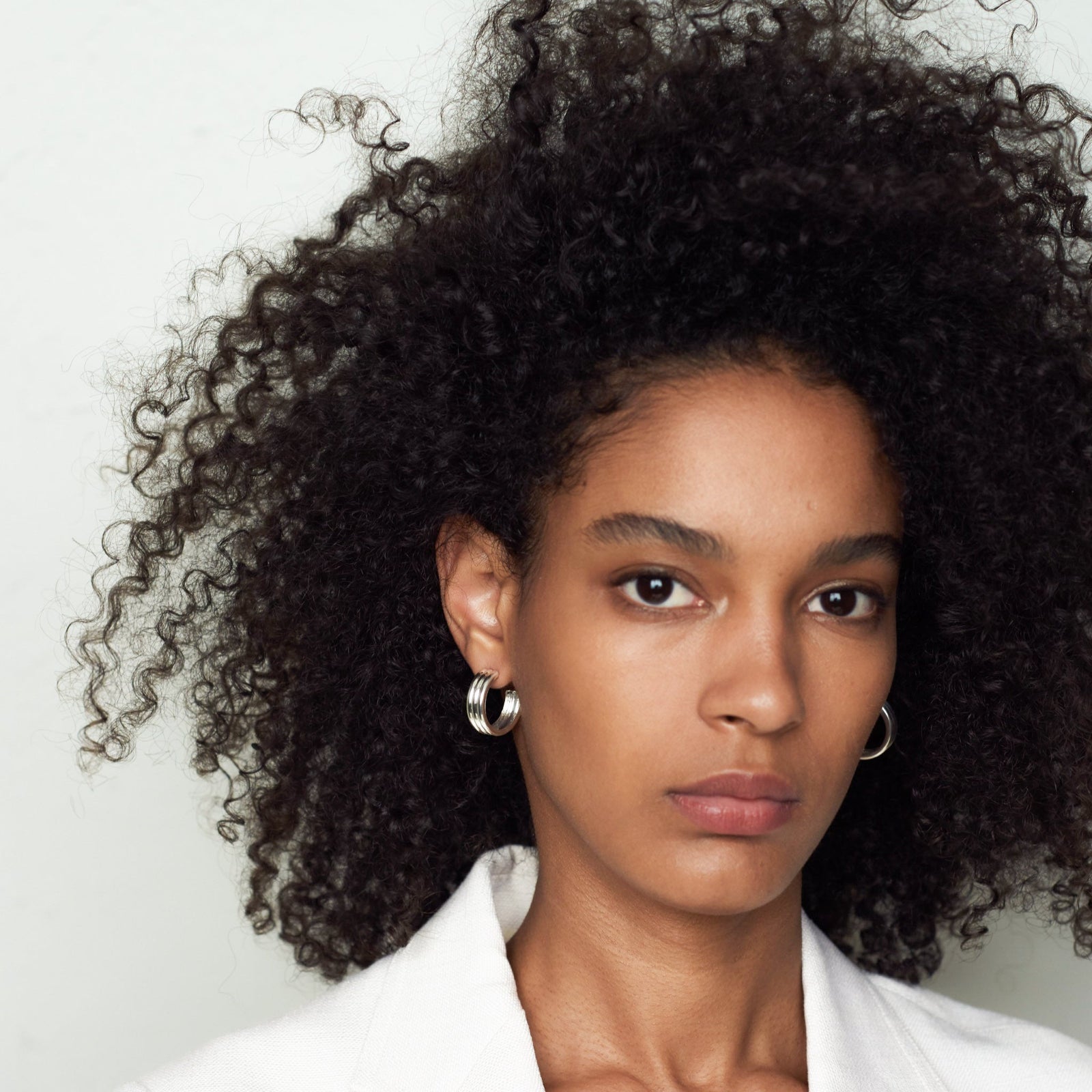 Woman wearing AGMES 0.925 sterling silver triple ridged medium hoop earrings.