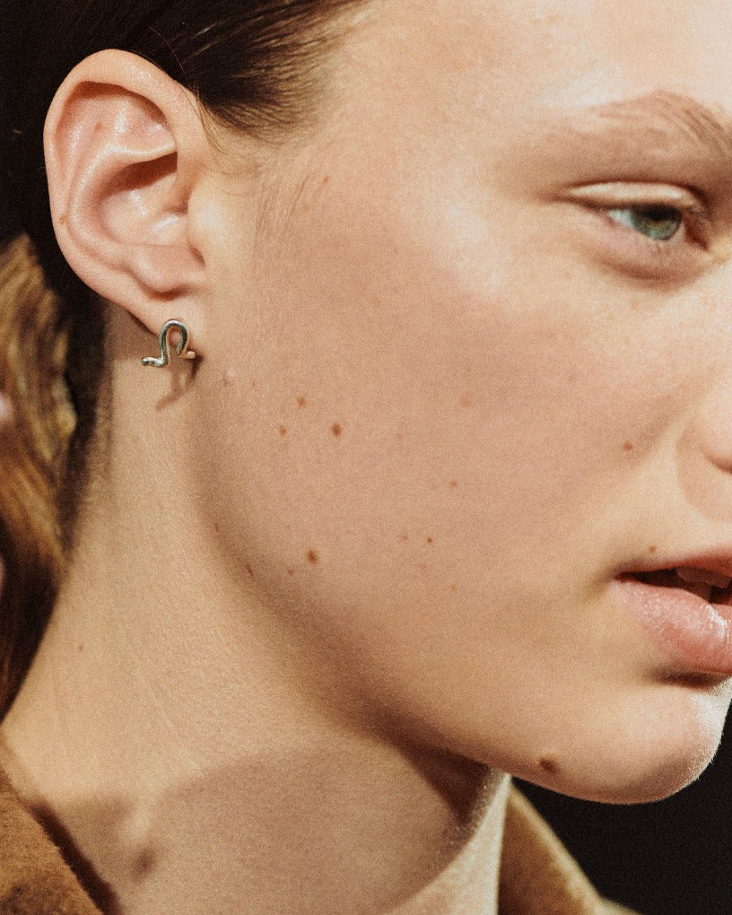 Woman wearing AGMES 0.925 sterling silver small twisted stud earrings.