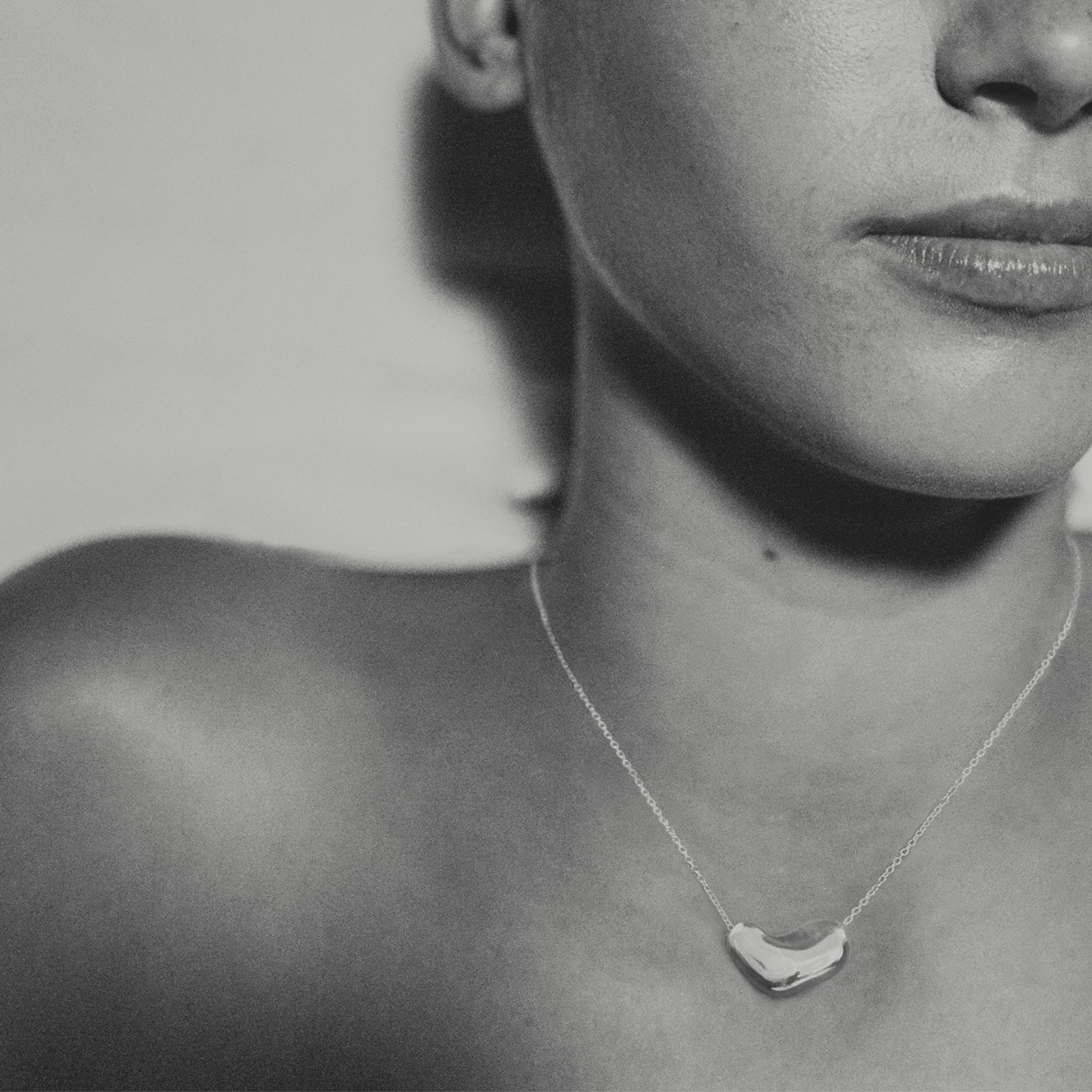 Model wearing AGMES .925 sterling silver Small Sculpted Heart Pendant Necklace. Black and white image.