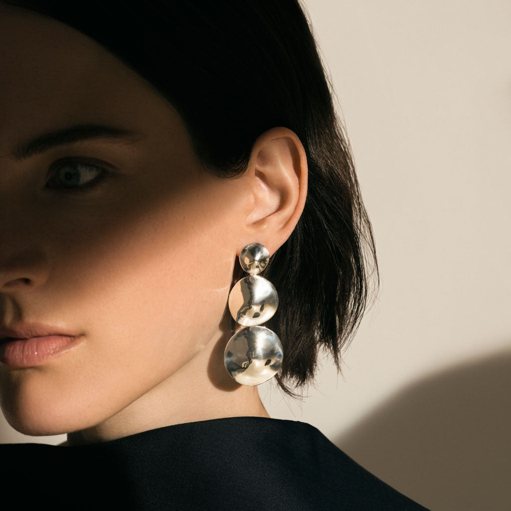 Woman wearing AGMES 0.925 sterling silver long circular round triple drop earrings.