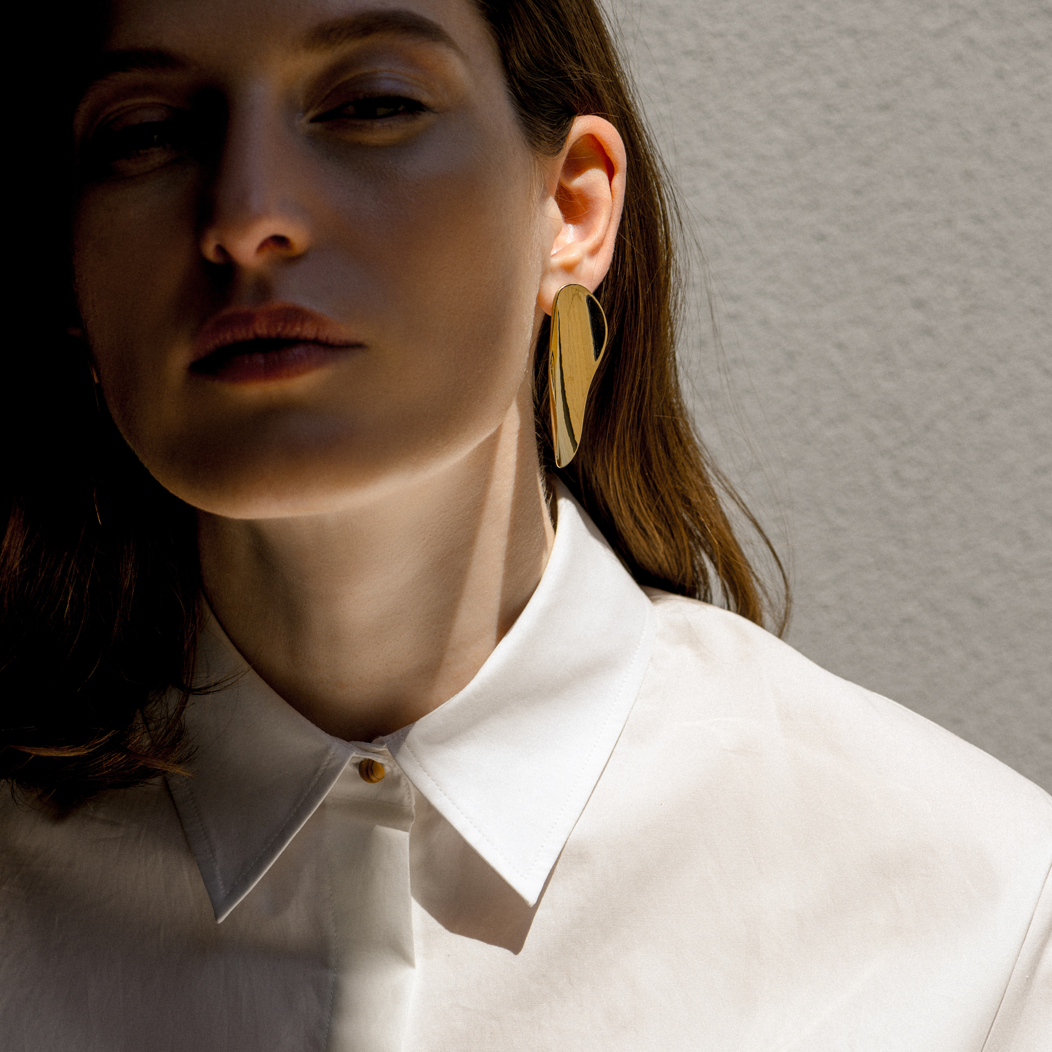 Woman wearing AGMES 18k gold vermeil long sculpted earrings. 
