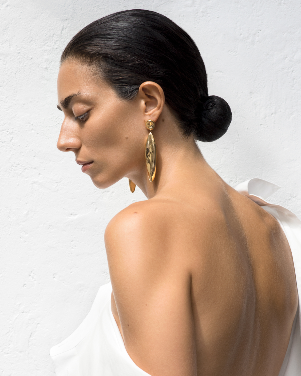 Woman wearing AGMES 18k gold vermeil sculpted drop earrings.